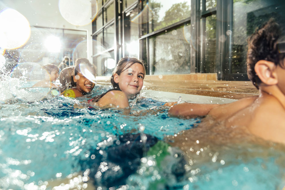 Barn som har simlektion i en inomhuspool.
